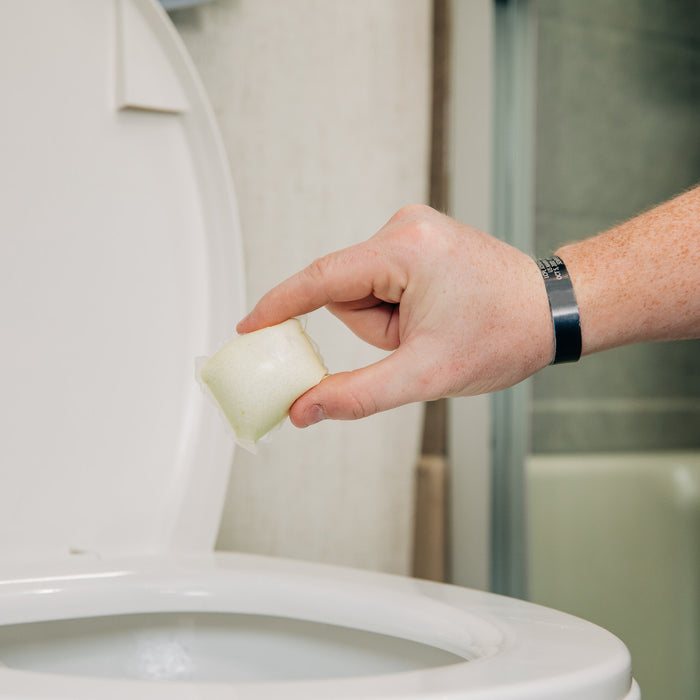 Hand dropping Camco TST RV toilet treatment packet into white RV toilet - In-Use Lifestyle | United RV Parts